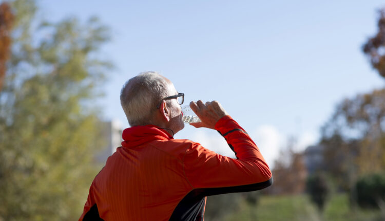 Senior runner drinking water after jogging